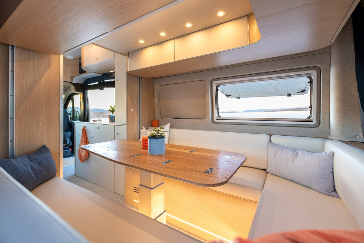 Modern rv rental interior: A bright, cozy dining area with a wooden table, bench seating, and a scenic window view. — photo 10