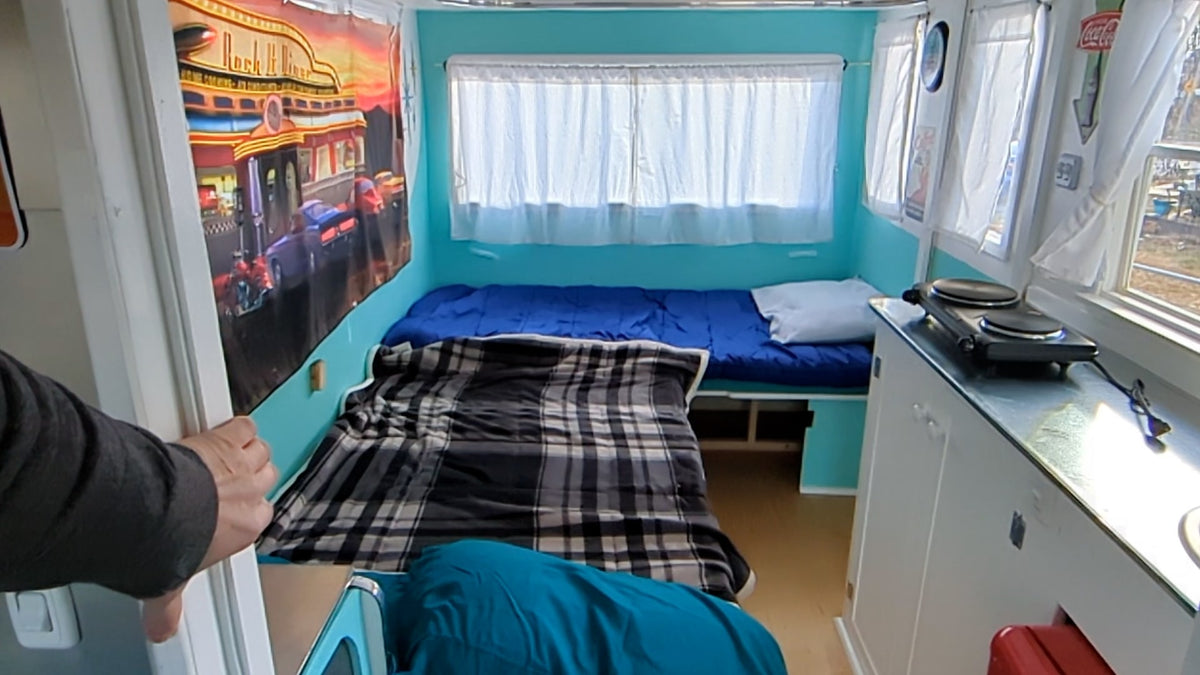 Vibrant rv rental: compact bed, two-burner hot plate kitchen, and retro diner-themed wall art adorn this cozy space. — photo 6