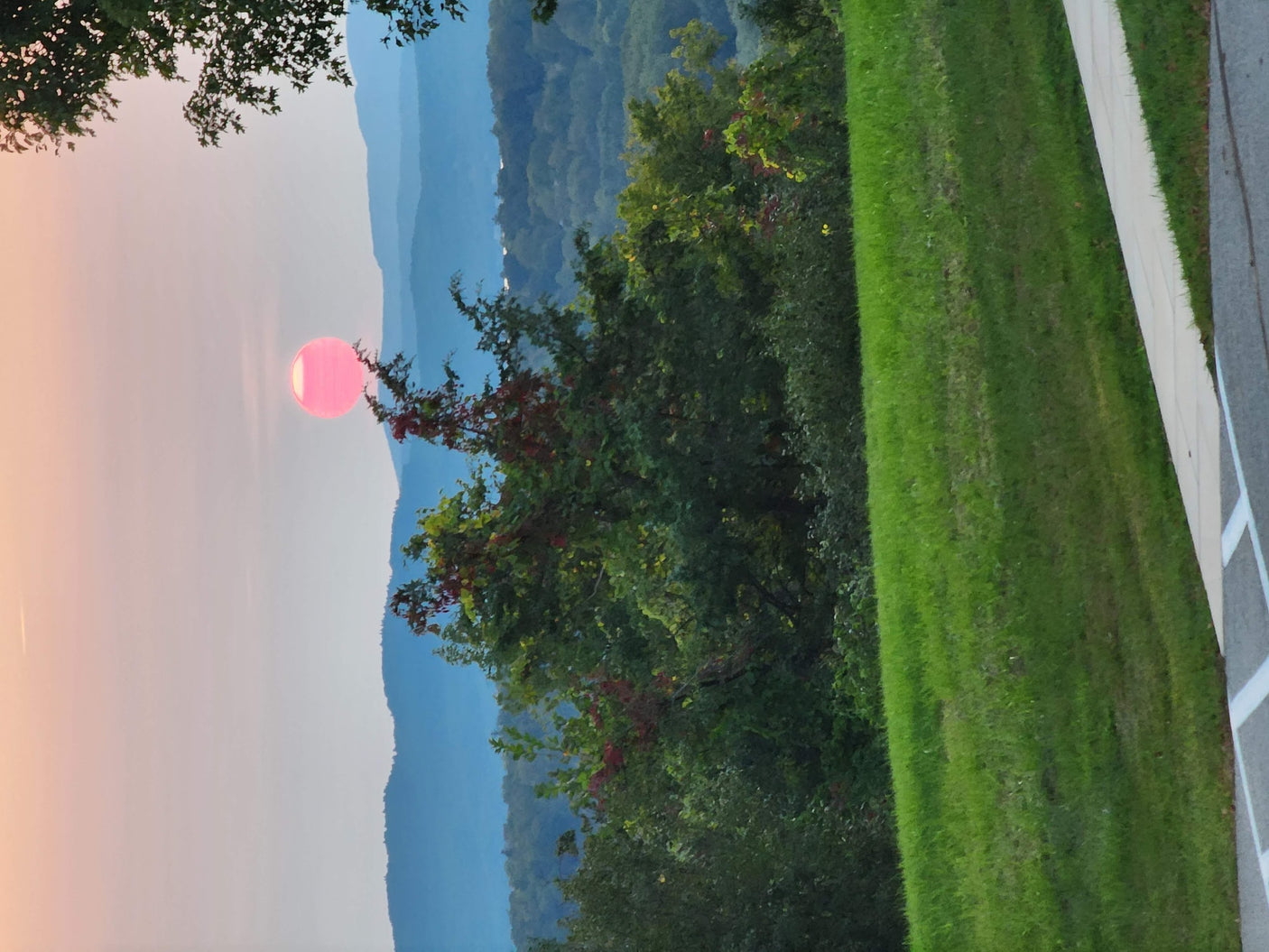 & fire pit under an overcast sky.|Striking pink sun sets over serene blue mountains and vibrant green trees