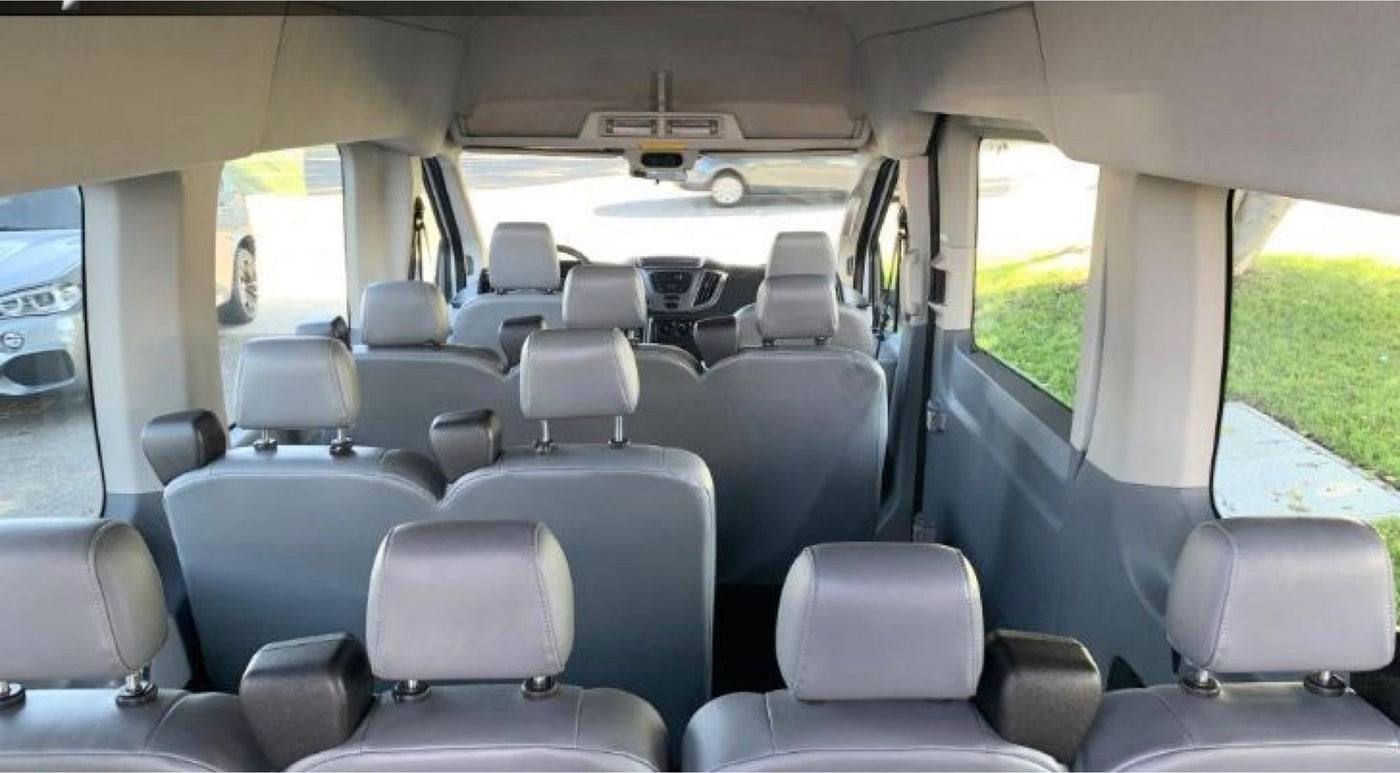 with soft light filtering through.|Inside an RV rental: a plush black bed with white stitching and custom wooden platform for comfort.|Spacious passenger van interior with multiple gray seats. Great for group trips — photo 3