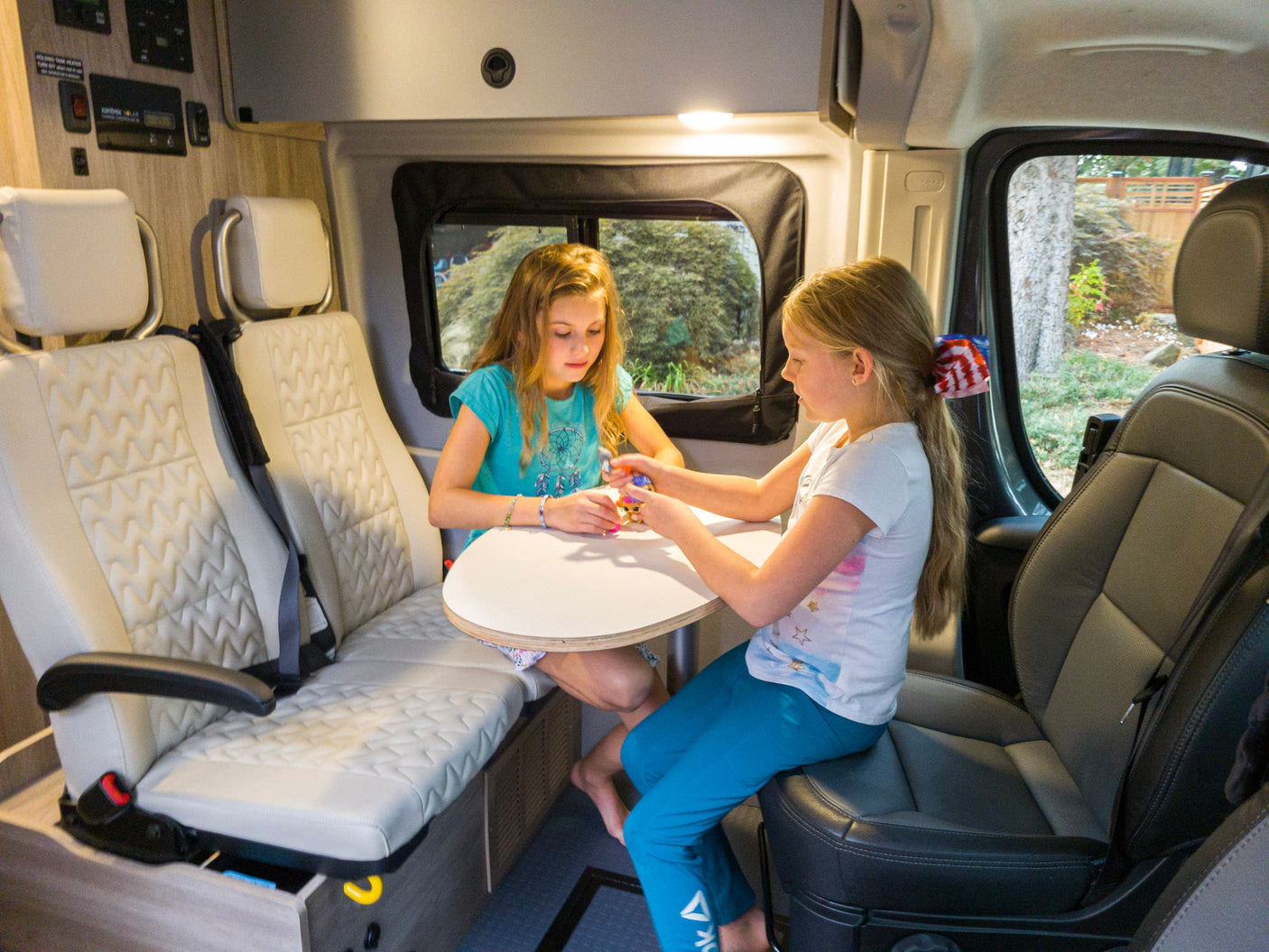 RV rental fun: Two girls play inside a comfy camper van, perfect for family adventures.