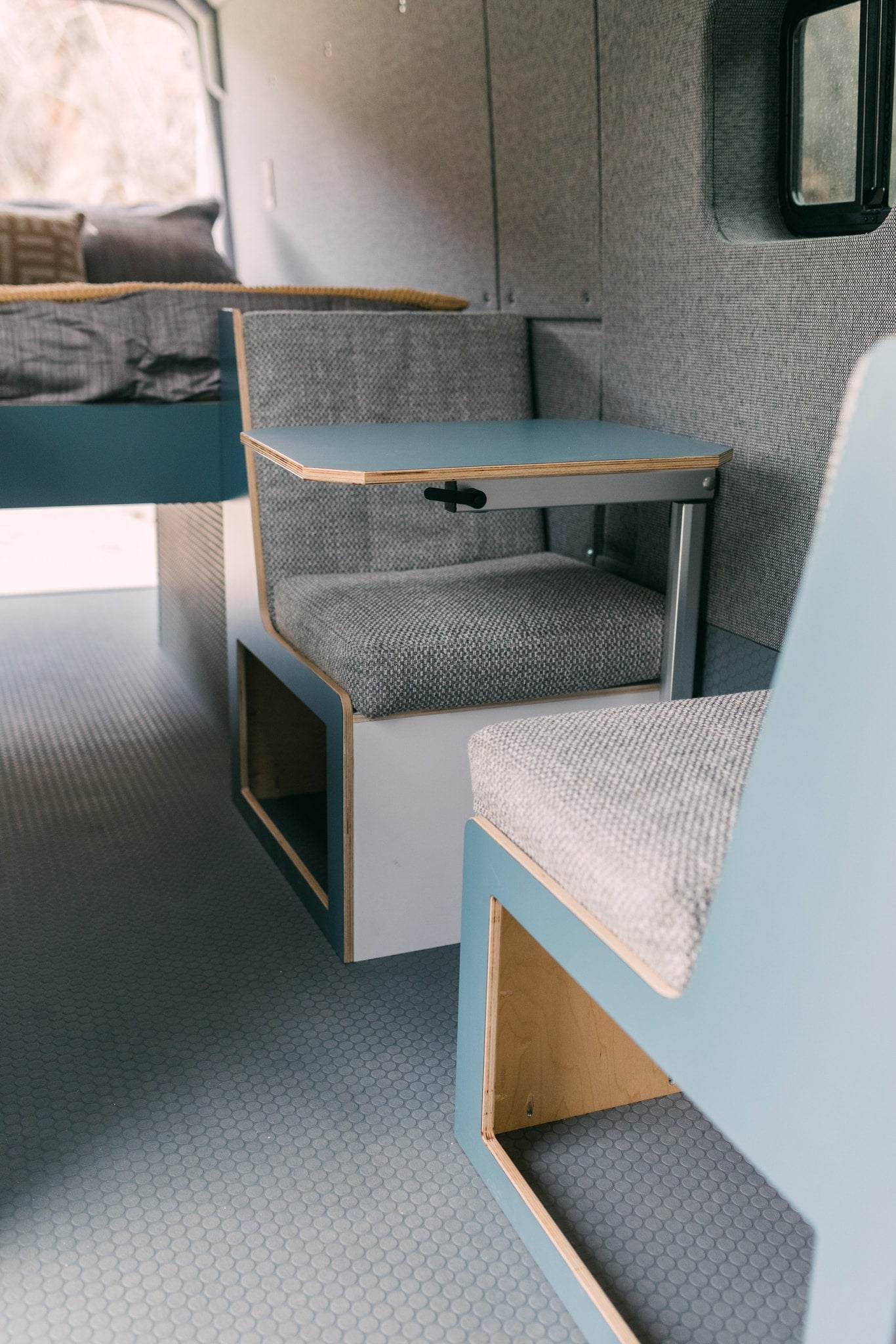 Clean RV rental interior: compact seating, removable table, and comfortable bed. Modern campervan design for travel. — photo 13