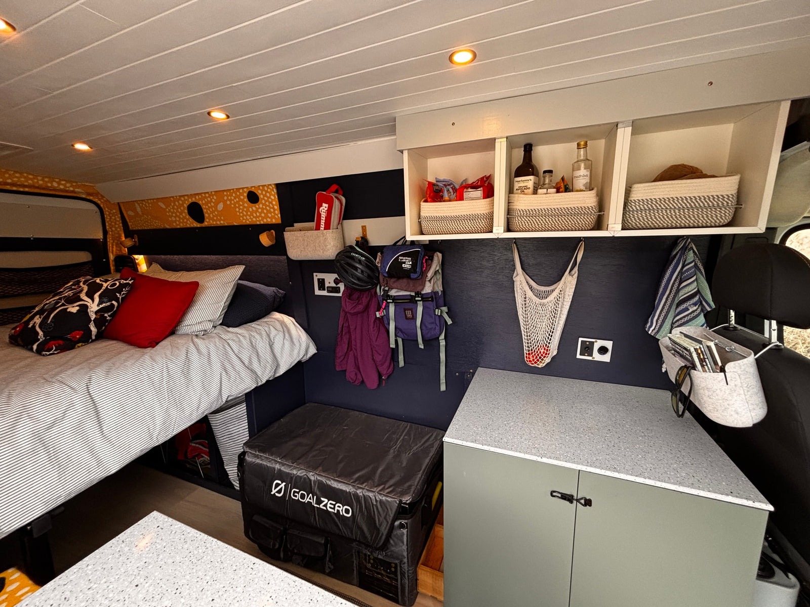 Cozy RV rental interior: comfortable bed, compact kitchen, smart storage, and a Goal Zero power station. Perfect for adventurers.