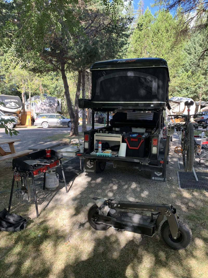 Rear of the trailer at camp with the tent deployed and the full-length prep table in use — photo 12