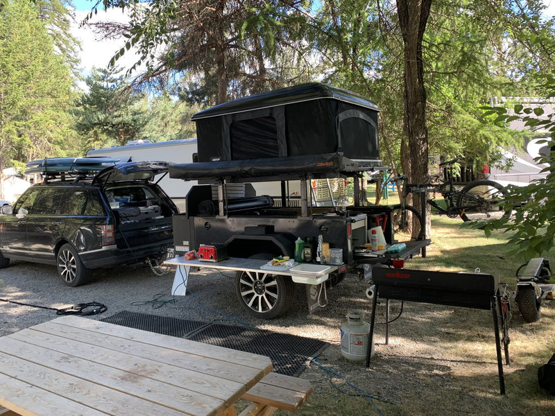 Camp setup in the pines with the galley boxes open and camp gear laid out on the prep table — photo 11