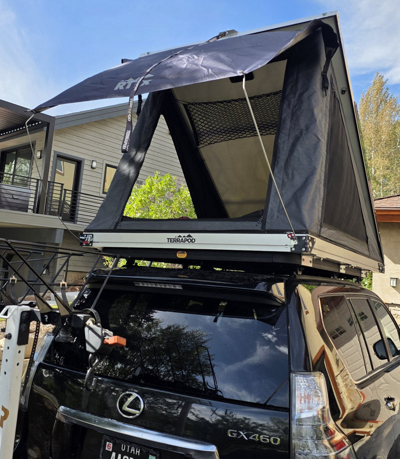 Rear view of the deployed Terrapod RTTx XL with the black RTTx rainfly guyed out over the entry, showing the mesh window panels, the TERRAPOD-branded side rail and the gear-loft netting inside — photo 3