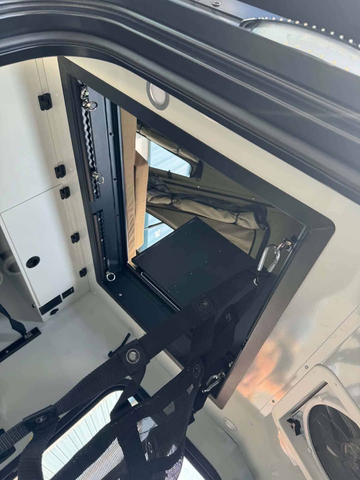 Upper pass-through hatch of the XPedition Voyager Sky XE propped open on its strut, with hammock straps and latching hardware visible from inside the cabin — photo 11