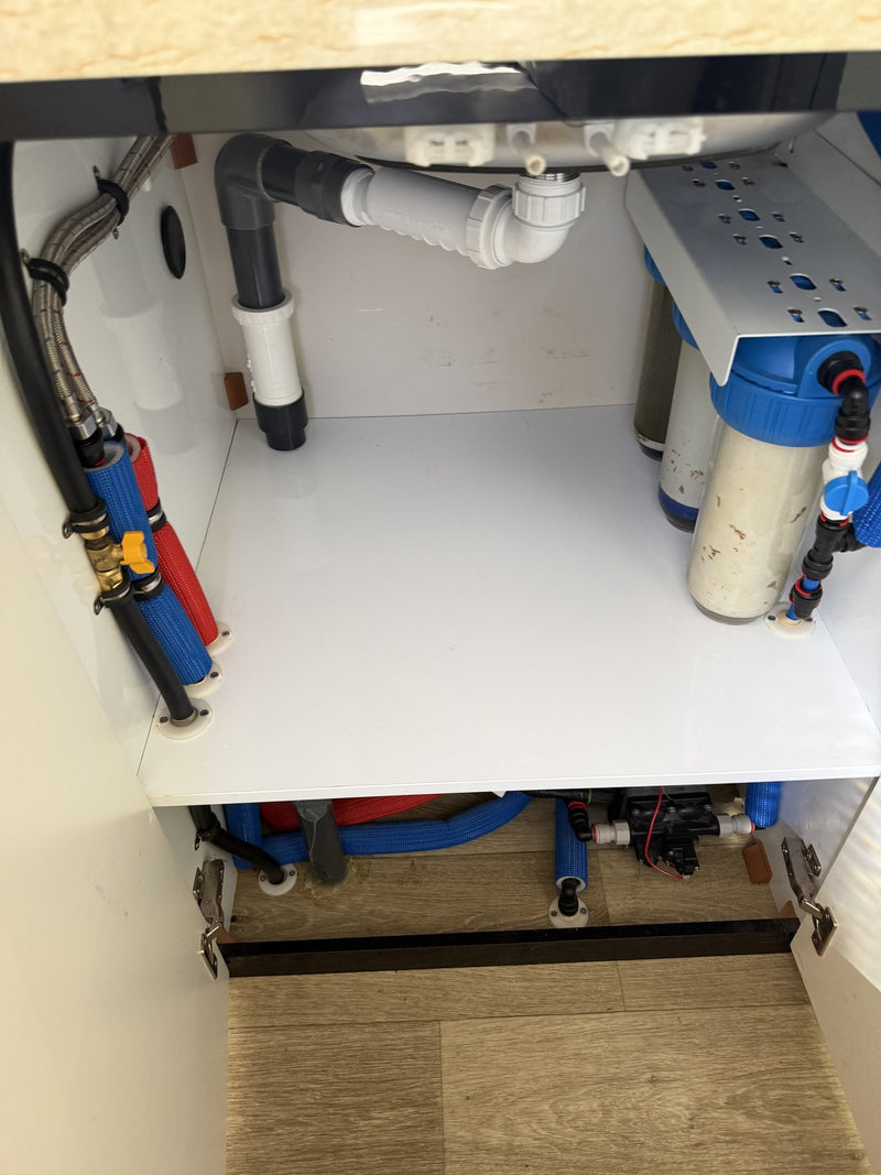 Under-sink cabinet opened to show the plumbing, braided supply lines, colour-coded pressure hoses and the twin inline water filter housings — photo 17