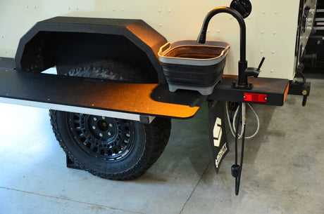 2014 Schutt Industries XVenture XV-2 overland trailer — upgraded alloy wheel with Cooper S/T Maxx tire beside the galley prep table