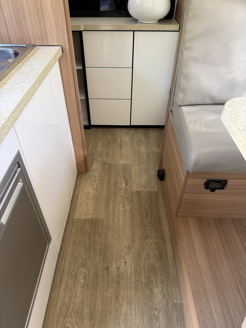 Vinyl plank flooring through the walkway between the galley and the dinette seat base, with cabinetry and drawer stack — photo 18