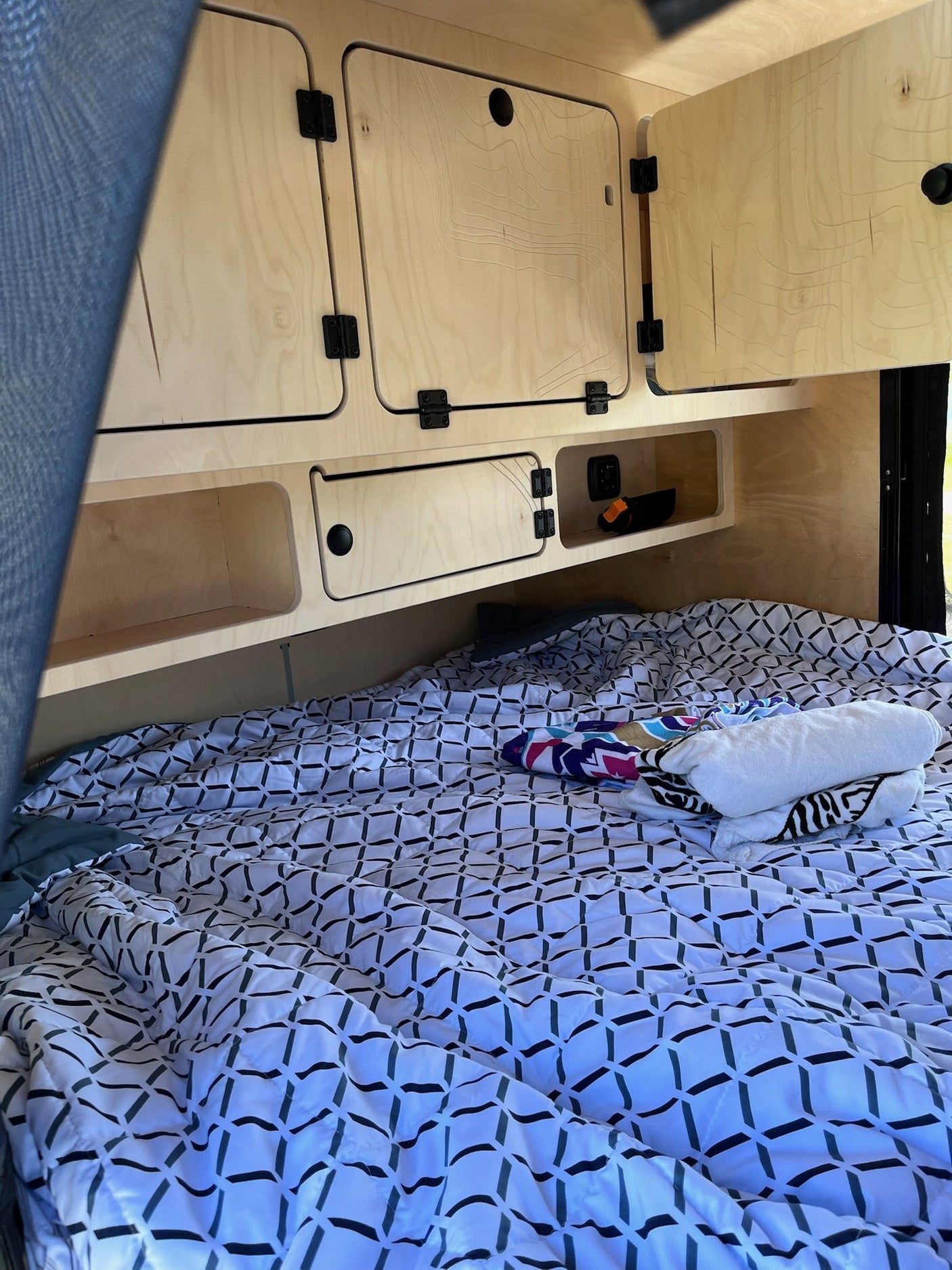 Escapod TOPO interior cabin with made bed and birch overhead storage cabinets