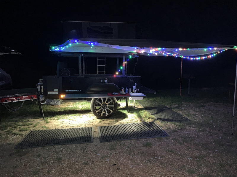 Night shot of the trailer with the awning out and string lights lit across the camp — photo 13
