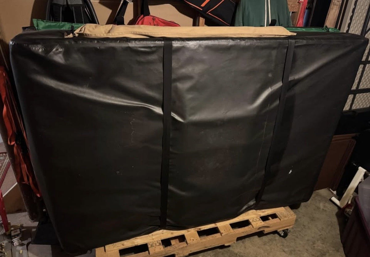 Folded rooftop tent in its travel cover, stored on a pallet in the garage — photo 5