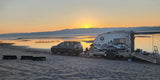 Trail Marker overland trailer with awning extended at a lakeside sunset
