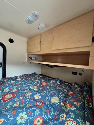 Overhead cabinet storage above the bed