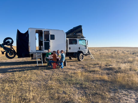 Family camp scene beside the Isuzu NPR with vertical bike rack mounted