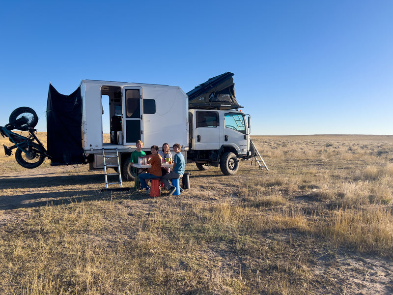 Family camp scene beside the Isuzu NPR with vertical bike rack mounted — photo 7