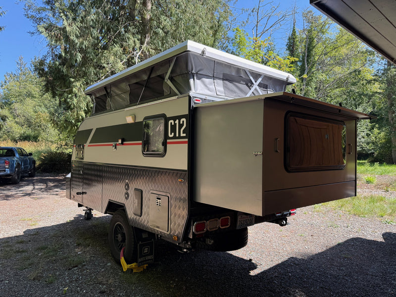 Rear three-quarter view of the C12 with the rear hatch open, showing the diamond-plate body and off-road suspension — photo 4
