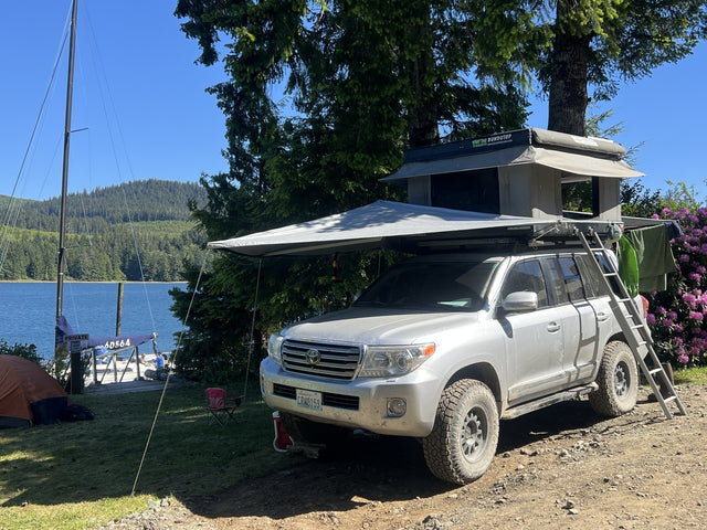Bundutop hardshell rooftop tent open on a Land Cruiser at a lakeside campsite