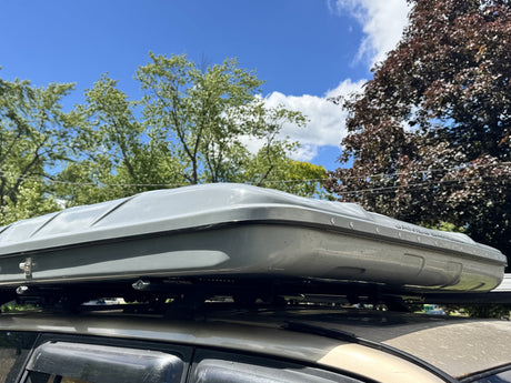 Side profile of the closed James Baroud hardshell tent mounted on a roof rack, showing the shell depth and mounting rails