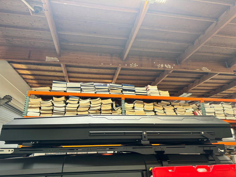 The closed Alu-Cab Gen 3-R rooftop tent seen from below on its roof rack, showing the full length of the shell and the rack crossbars underneath — photo 9