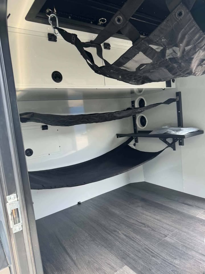Interior of the XPedition Voyager Sky XE with the gear and bunk hammocks rigged along the wall, wood-look vinyl plank flooring, folding side shelf and speaker ports — photo 8