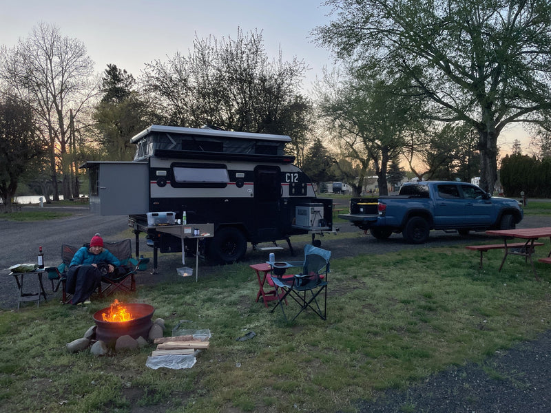 The C12 set up at a campsite at dusk with camp chairs, a fire going and the tow truck parked alongside — photo 19