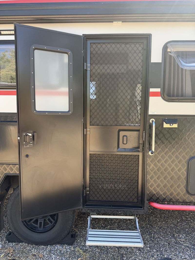 Entry door standing open with the mesh security screen closed, showing the door latch, interior-facing window and the pull-down aluminum entry step over the black alloy wheel — photo 5