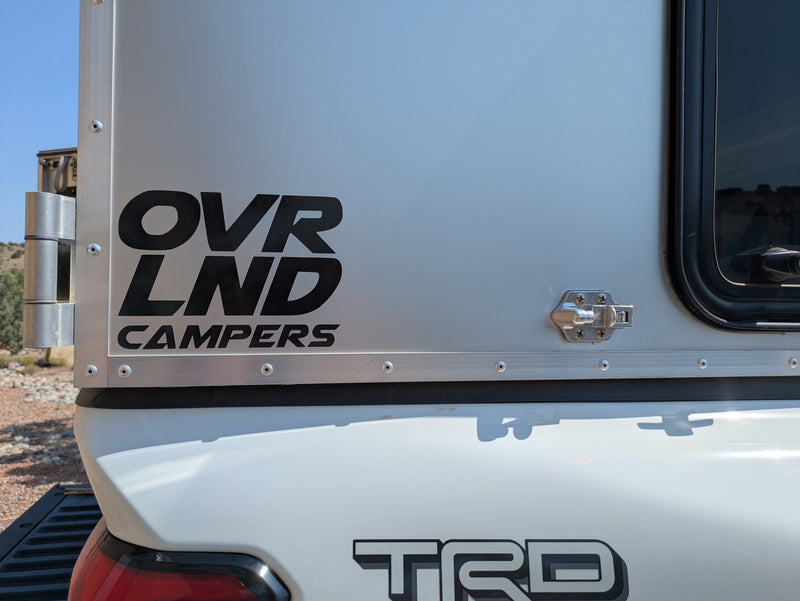 OVRLND Campers badge on the anodized silver aluminum skin above the Tacoma TRD tailgate — photo 8