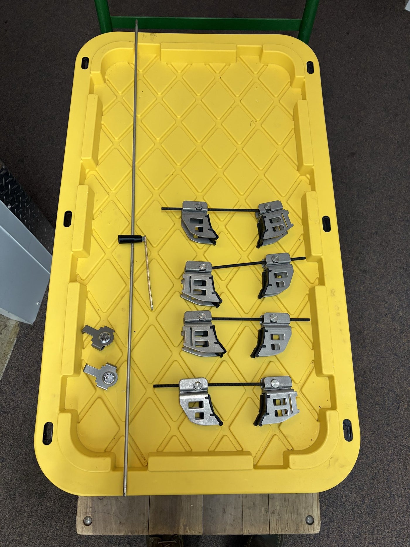 Eight metal crossbar mounting clamps with their bolts laid out in rows, alongside a long adjustment rod and two locking end caps with keys — photo 11