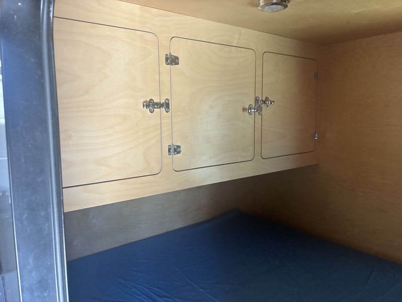 Cabin interior showing the sleeping area with mattress, birch overhead storage cabinets and a dome light — photo 5