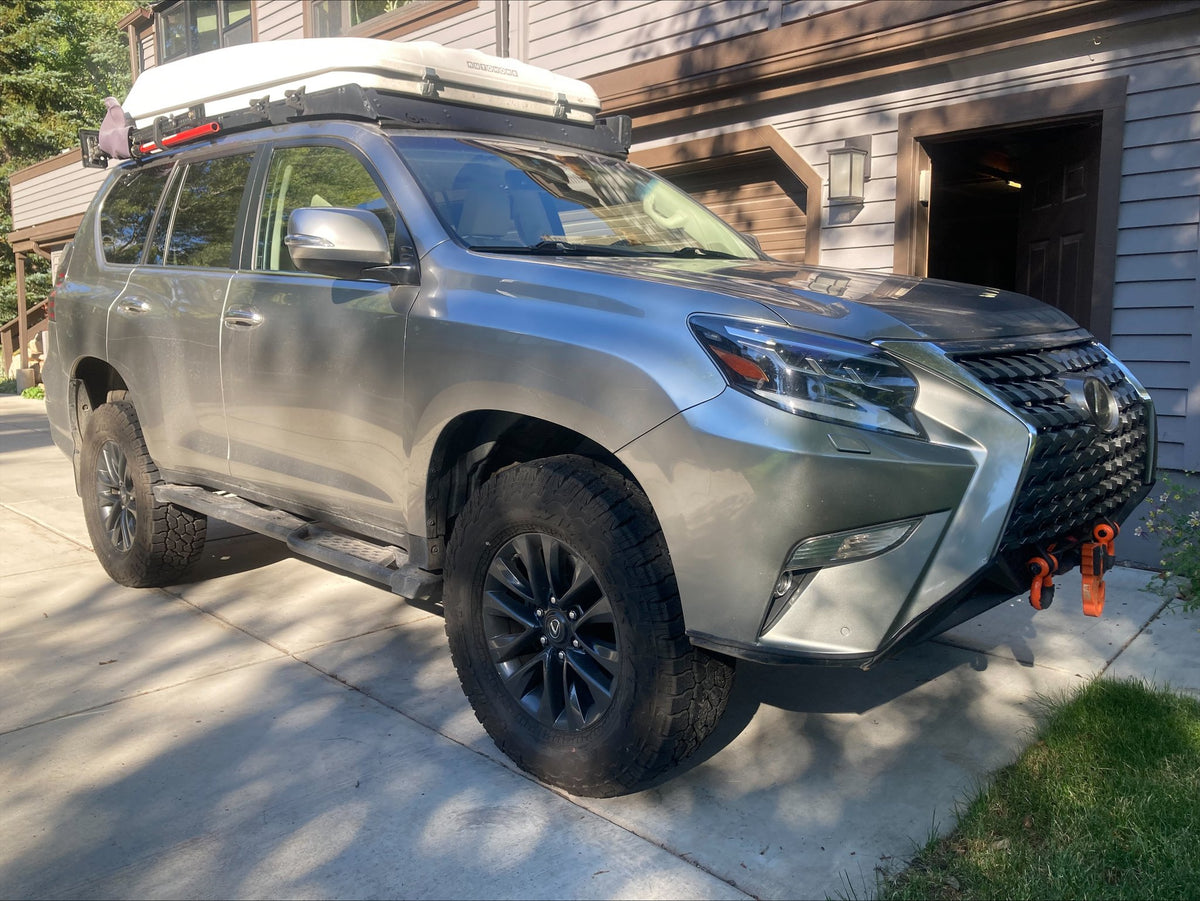 2021 Lexus GX460 overland build, front passenger-side three-quarter view in silver — CBI front bumper with recovery shackles, Prinsu roof rack carrying an Autohome rooftop tent, on Falken all-terrain tires — photo 1