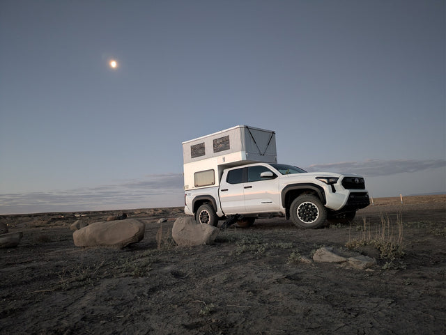 Rear barn doors open with the tailgate down, showing the truck bed and camper entry