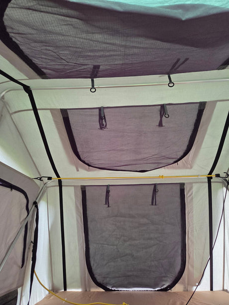Inside the rooftop tent showing mesh windows and ceiling vents