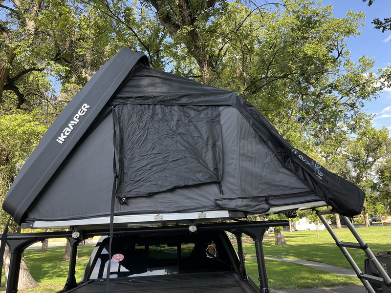 Side profile of the Skycamp 3.0 Mini set up, showing the Rocky Black hardshell with iKamper branding, grey tent body and zippered side window — photo 2