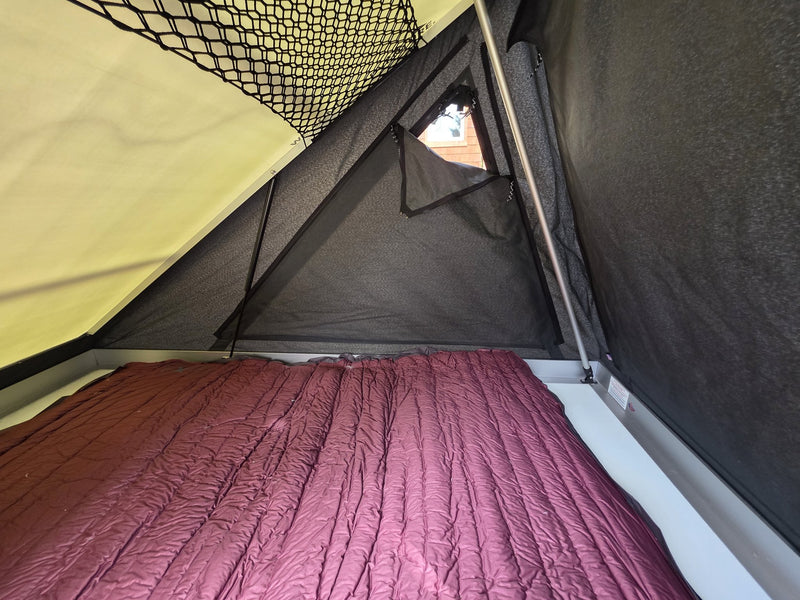Interior of the Terrapod RTTx XL rooftop tent showing the burgundy Exped MegaMat Max Duo double sleeping pad laid out across the full floor, the mesh gear loft overhead and a zippered no-see-um mesh window — photo 4