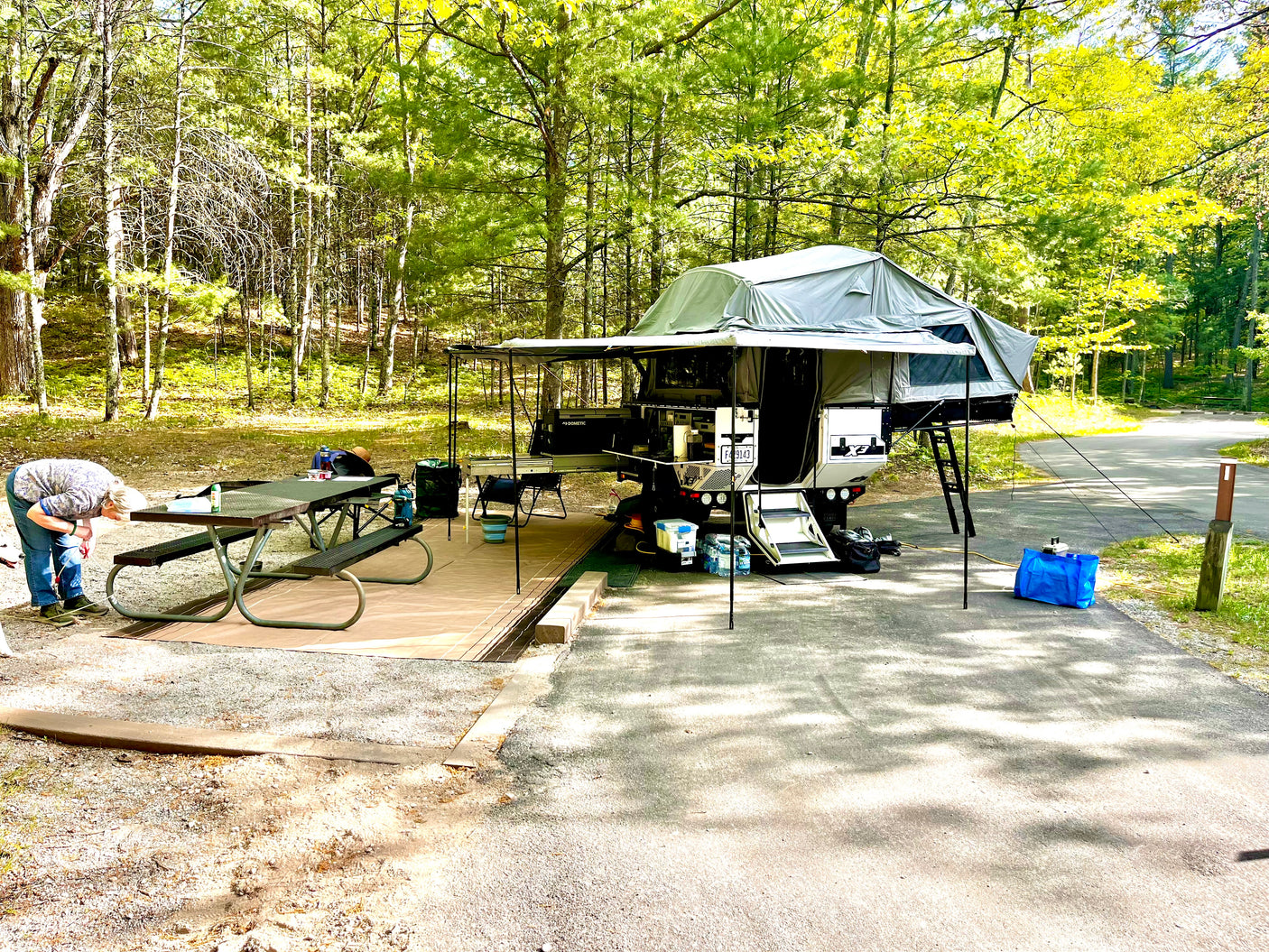 Campsite setup with awning and wall kit deployed, picnic table alongside