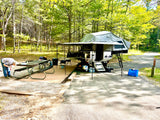 Campsite setup with awning and wall kit deployed, picnic table alongside