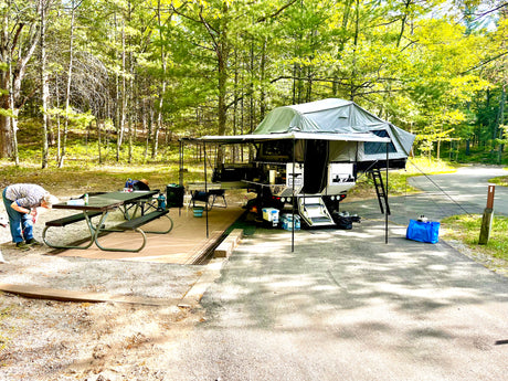 Campsite setup with awning and wall kit deployed, picnic table alongside