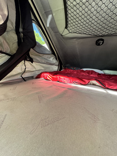 Interior of the tent looking toward the side window, showing the full-size James Baroud mattress and bedding