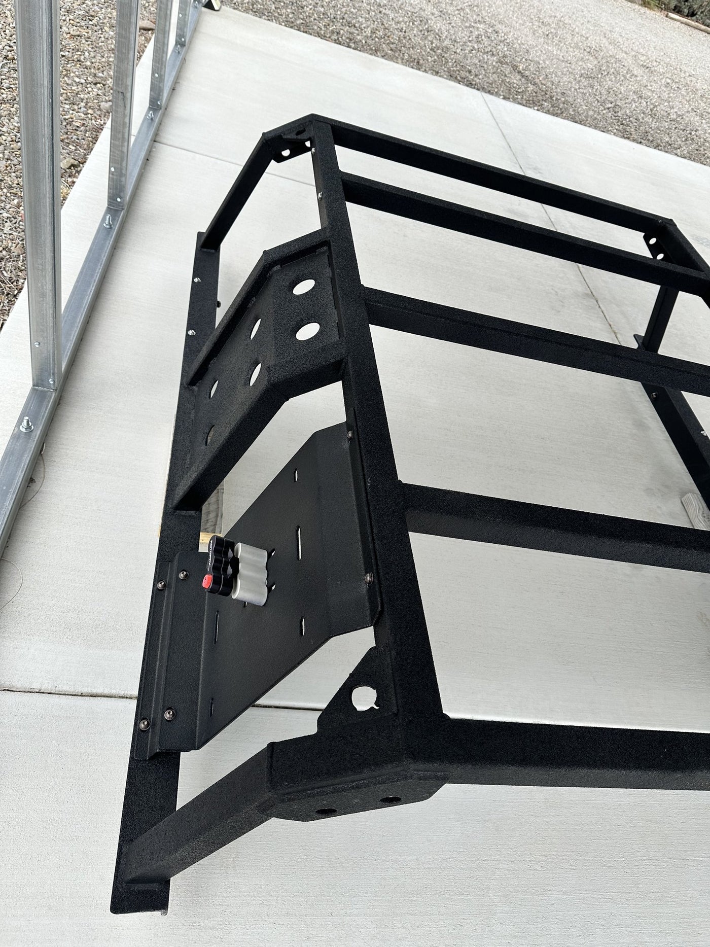 Three-quarter view of one upright showing the side plate with cutouts, the universal mounting plate carrying a Rotopax locking mount, and the bed mount bracket below — photo 3