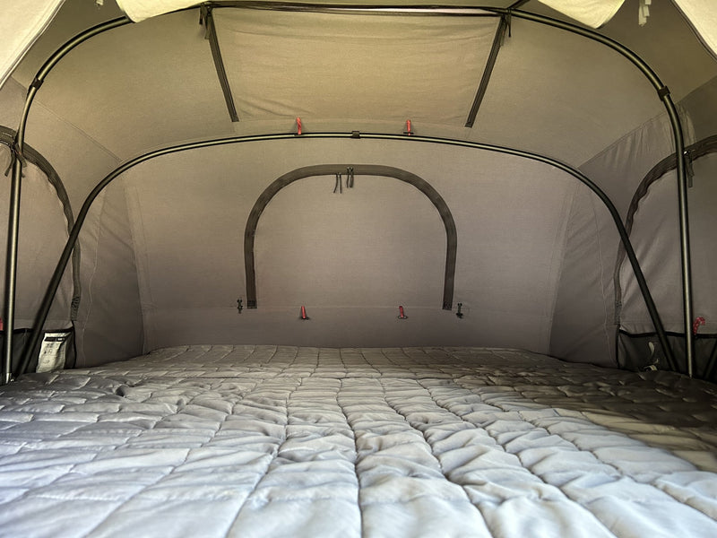 Interior view toward the back wall showing the full-width quilted mattress, the insulated inner tent panels, the arched rear window cover and internal attachment points — photo 5