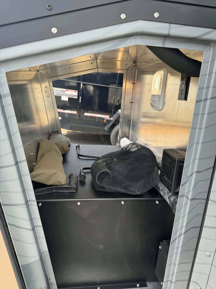 Front nose storage compartment of the XPedition Voyager Sky XE, aluminum-lined with gear stowed inside, an interior dome light and a 120V outlet — photo 10
