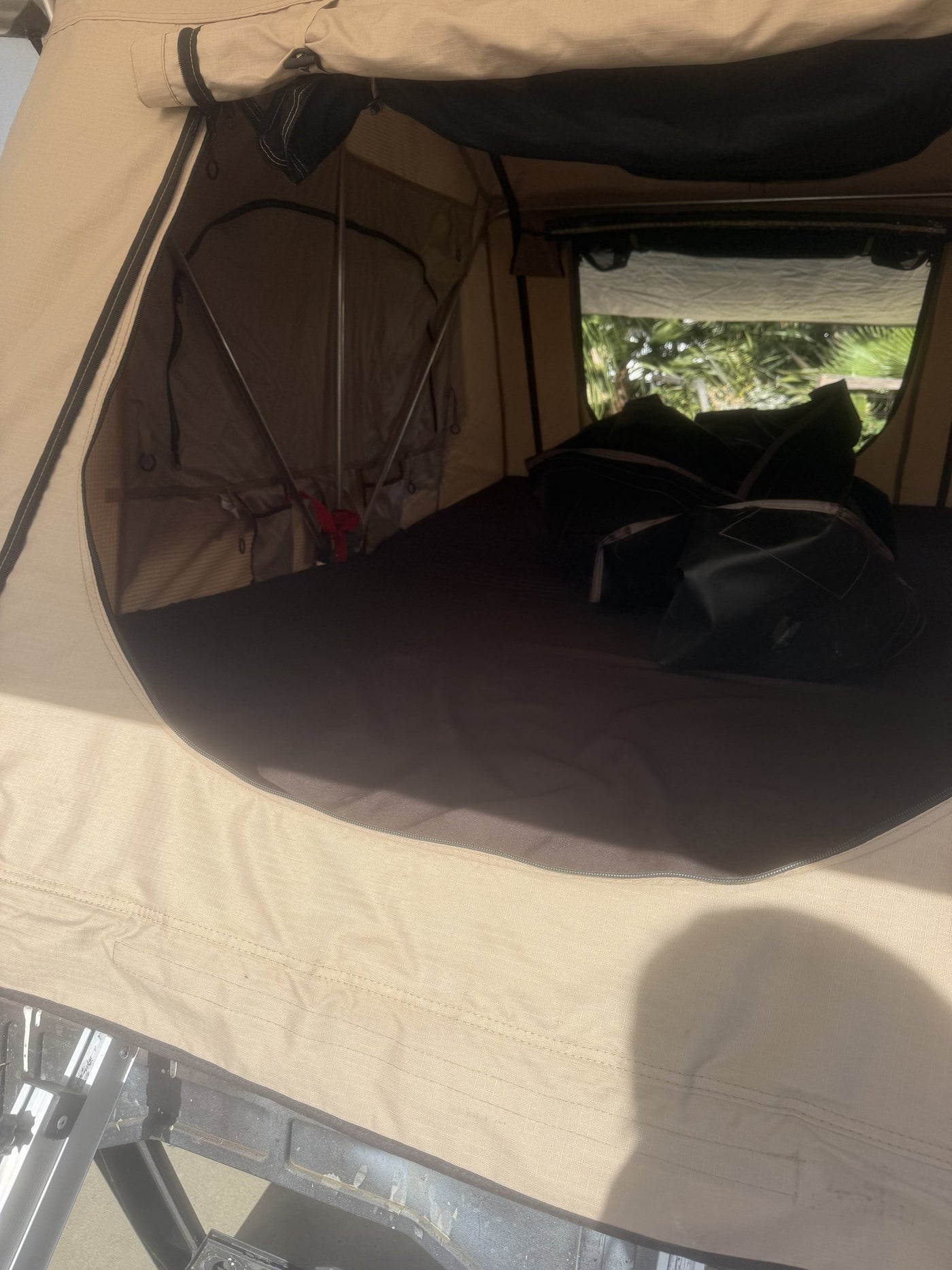 Looking into the tent through the open door at the clean queen mattress and the folded travel cover — photo 9