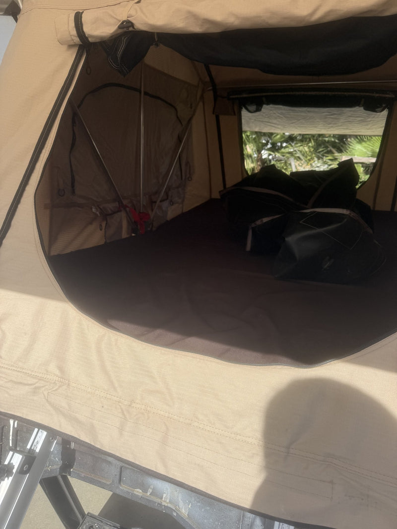 Looking into the tent through the open door at the clean queen mattress and the folded travel cover — photo 9
