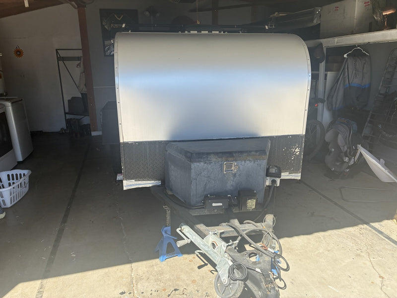 Front view of the teardrop trailer with the A-frame tongue, coupler, jack stand, battery box and diamond-plate front skirt — photo 3