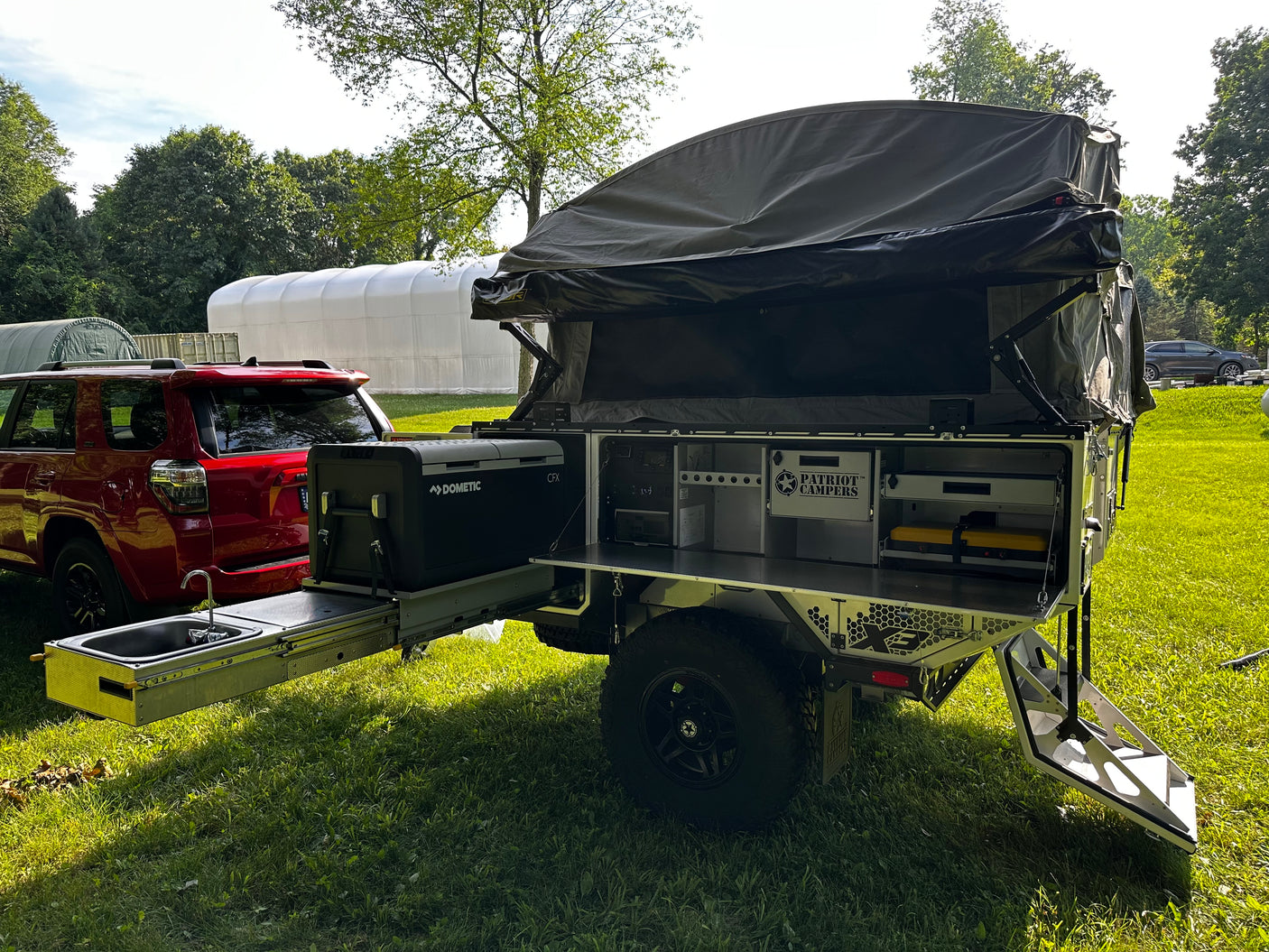 2022 Patriot Campers X3 overland trailer, tent up with rear galley kitchen open, three-quarter rear view