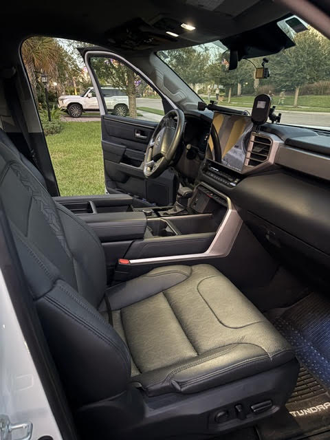 Cab interior from the passenger door: black leather seats, centre console, large touchscreen and the Bulletpoint RubiGrid dash mount with phone holder — photo 18