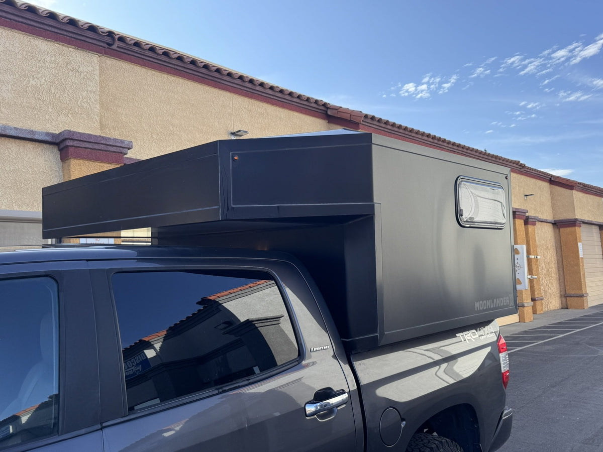 Side profile of the Moonlander X on the Tundra showing the full-length cab-over overhang and black anodized panels — photo 4