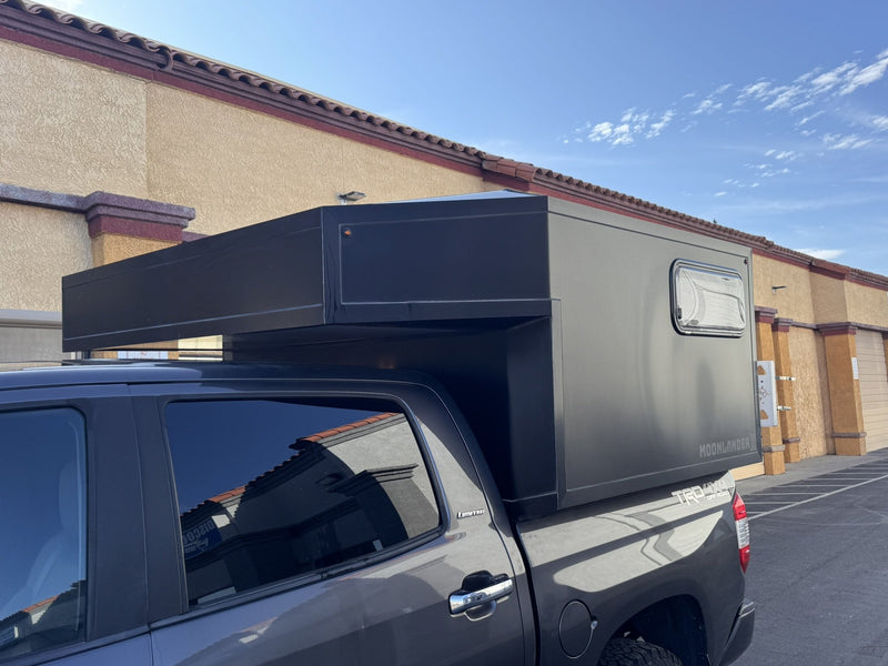 Side profile of the Moonlander X on the Tundra showing the full-length cab-over overhang and black anodized panels — photo 4